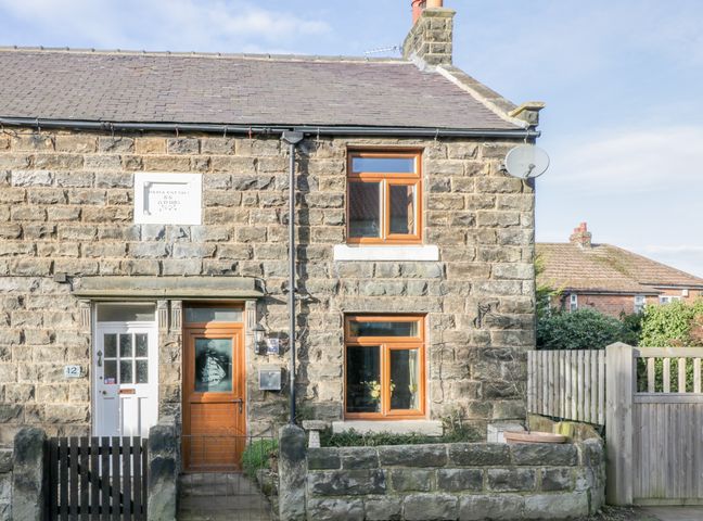Stone cottage exterior with two wooden framed windows two doors and a small garden at Eskside Cottage in Sleights