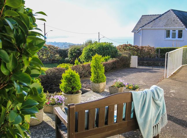 A garden with potted plants and flowers and a wooden bench with a blanket at Garnedd Lwyd in Llanfair