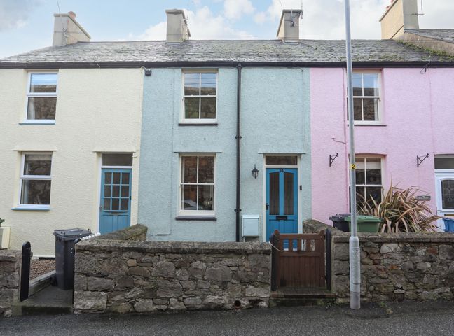 A row of three connected houses with stone walls and blue doors at 14 Rose Hill in Beaumaris