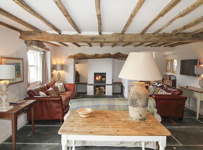 A living room with exposed wooden beams two red leather sofas and a fireplace at Ty Mawr Porthmadog in Porthmadog