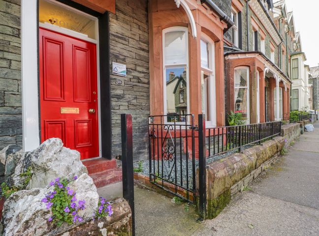 A row of stone houses with a red door and black metal gate at Sefton House in Keswick