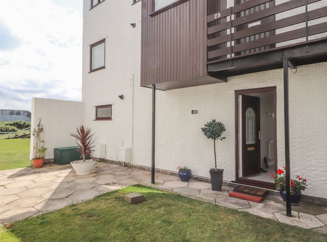 An entrance to a ground floor flat with open door potted plants and a tiled patio at Sunset Sands in Deganwy