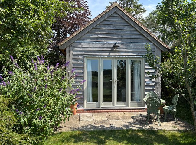 A garden with a building featuring glass doors at The Lodge at Mortons in Hankerton