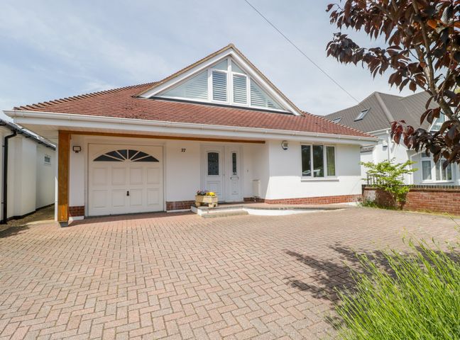 A front view of a house with a garage driveway flower pot and tree at 27 Wick Lane in Christchurch