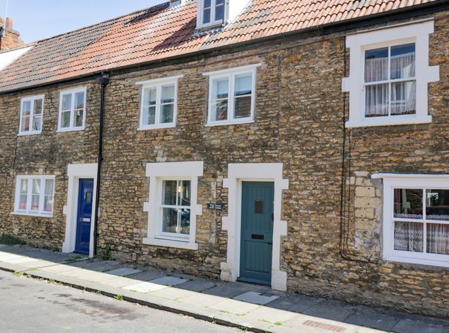 A street view of stone cottages with blue doors and white window frames at Troopers Cottage in Frome