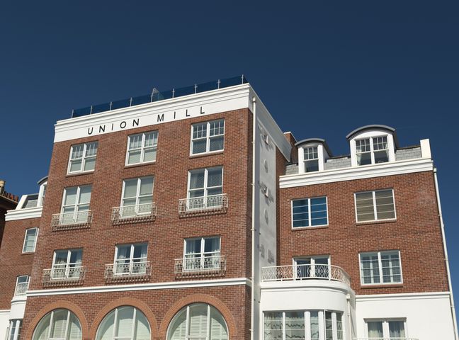 A multi-story brick building with multiple windows under a clear sky at Union Mill