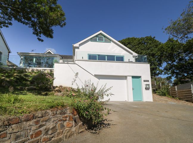 A modern white house with blue doors and windows with a driveway and glass balcony at Argraig in Llanbedrog