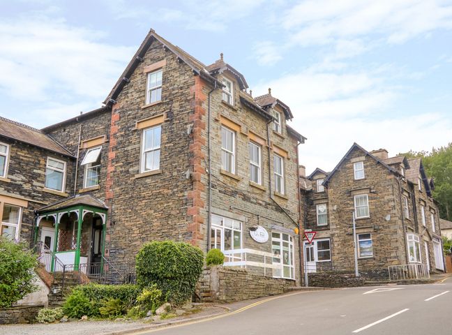 Traditional stone buildings by a curved road with greenery at Rooftops in Coniston