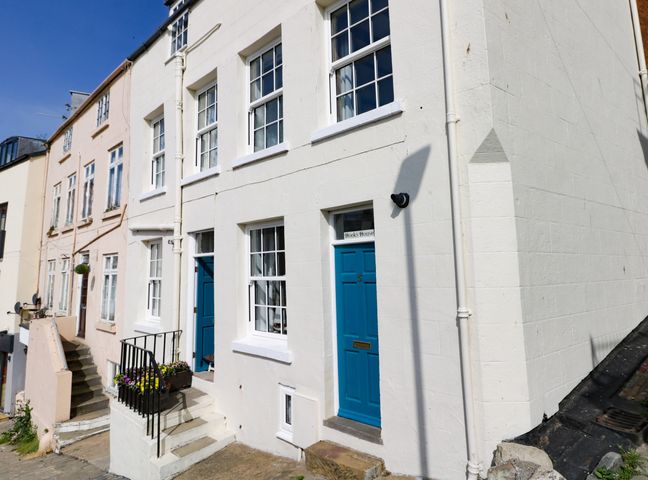 The exterior of a white building with blue doors and multiple windows on a street at Hooks House in Scarborough