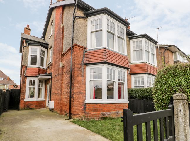 A two story brick house with white framed bay windows and a black gate at Beach House in Bridlington