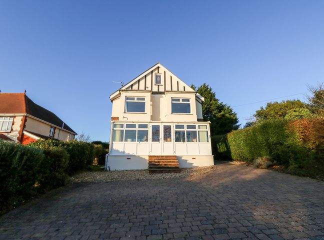 A detached two-story house with a front porch and paved driveway surrounded by hedges at 5 The Mall in Sandown