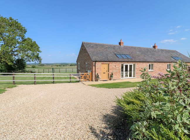 A house with a gravel driveway and green fields at Mandarin Cottage in Melton Mowbray