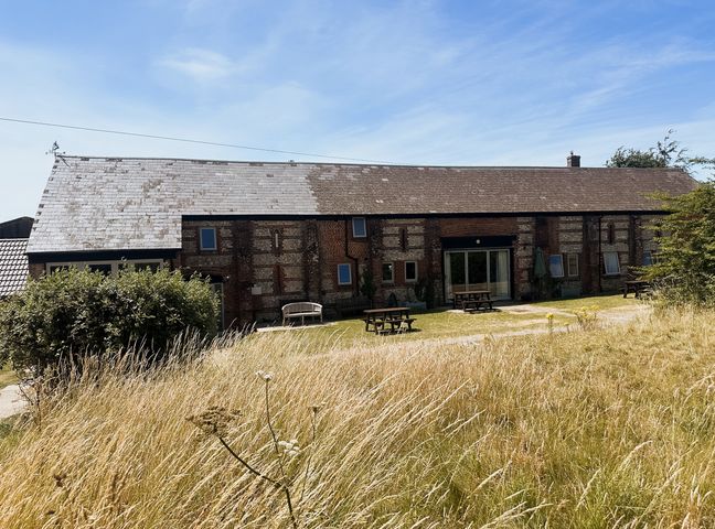 A building with tables and chairs in an outdoor area at Newfield Farm Cottages in Pimperne near Blandford Forum