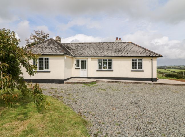 A single story house with a gravel driveway and grass lawn at Summercourt in Tremaine