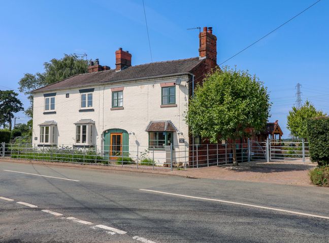 A house with a fence and trees at Bellamour End Cottage in Rugeley