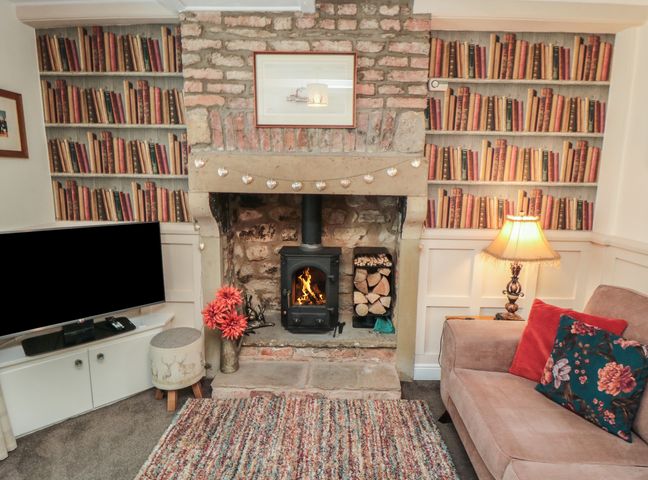 A living room with a fireplace and television at Dove Cottage in Pickering