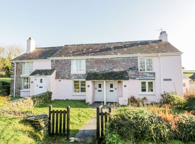 A pink stone cottage with two front doors and a small black gate at 3 Rose Cottages Lansallos near Polperro