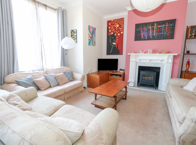 A living room with sofas a coffee table a fireplace a television and wall art at Victorian Town House in Weymouth