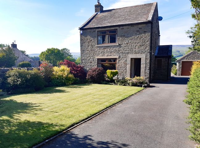A stone house with two windows and a driveway next to a lawn with bushes at Westholme Mickleton Teesdale
