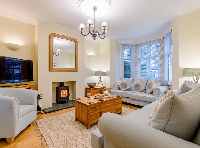 A living room with two sofas a wooden coffee table a television and a fireplace at Oak House in Keswick
