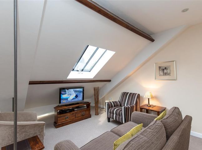 A living room with a sofa and armchairs a television and a skylight window at The Gallery in Grasmere