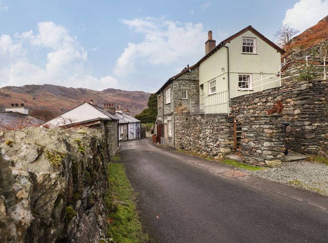 A narrow road lined with stone wall houses and a mountainous background at Underfell in Chapel Stile
