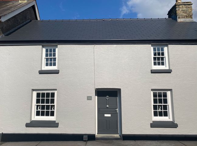 Front view of a white house with black door and window frames at Awelfa in Newport Pembrokeshire