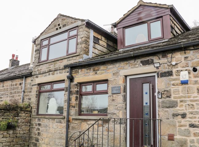 Stone exterior of a building with brown framed windows and a door with steps at Little Barn in Cross Roads near Haworth