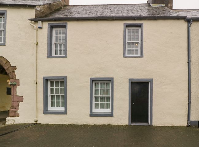 A beige building facade with four windows and a black door at The Pend in Whithorn