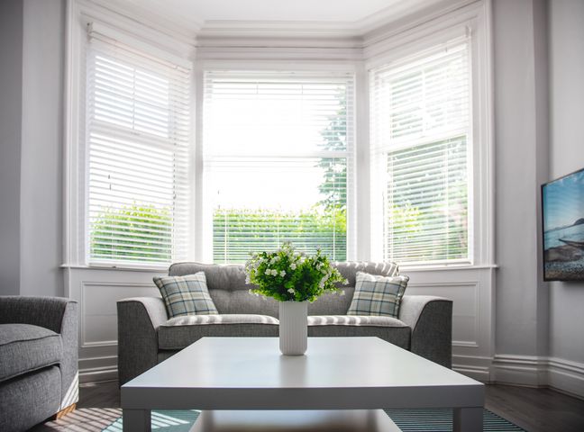 A living room with a white coffee table and a gray sofa with pillows at Oxford House in Llandudno