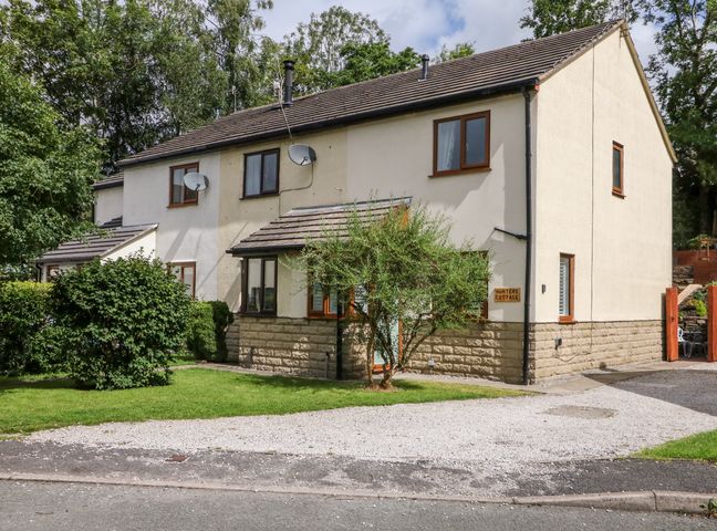 A two story house with satellite dishes trees and a driveway at Hunters Cottage in Chinley