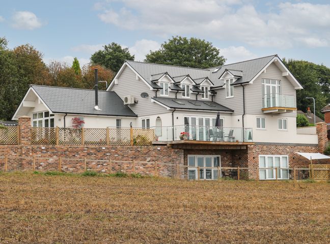 A large modern house with grey roofing and brick lower walls surrounded by trees at Slitting Mill Annex in Cannock Chase Forest Rugeley Staffordshire