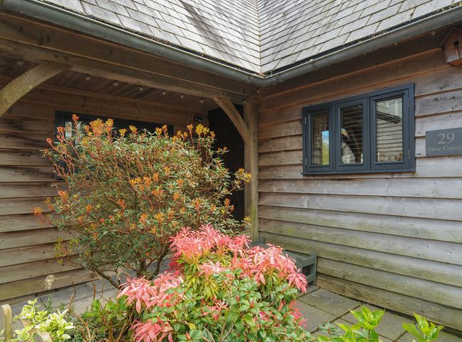 An entryway with wooden walls and roof with shrubs in front at Stow Cottage in Davidstow near Camelford