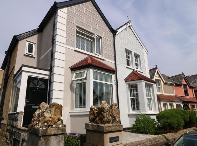 A row of attached houses with bay windows and small front gardens at Elsinore in Conwy