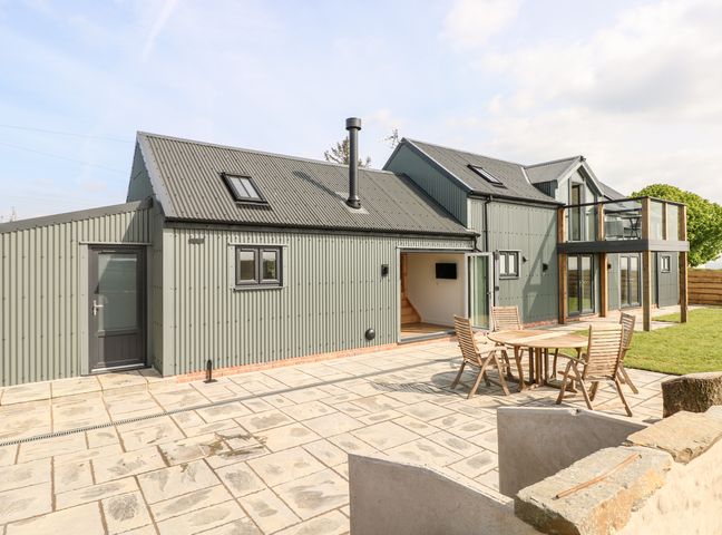 Modern two story house with patio furniture on stone paved area and grass lawn at Glowty Brynbedw in Efailwen