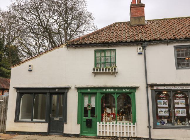 A row of shops including Resourceful Living with green door and window and Craven Holmes estate agents with property listings displayed at The Hideaway in Boroughbridge
