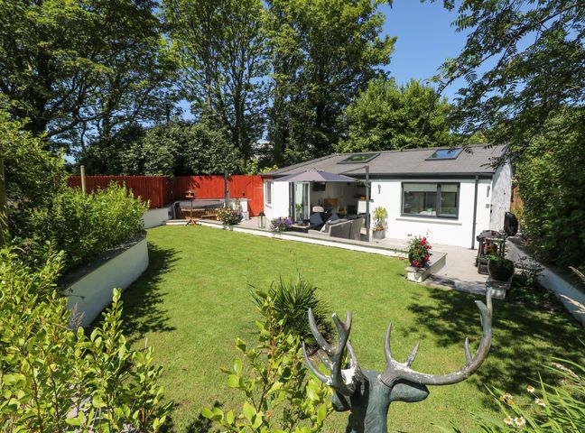 A garden with lawn shrubs and a patio area with outdoor furniture at Summerhouse in Penally