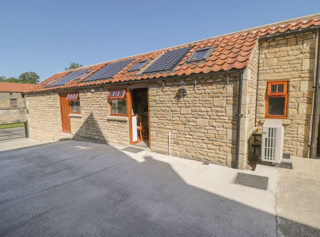 Exterior view of a stone building with a tiled roof and solar panels at Yeoman's Cottage Allerston near Thornton-Le-Dale