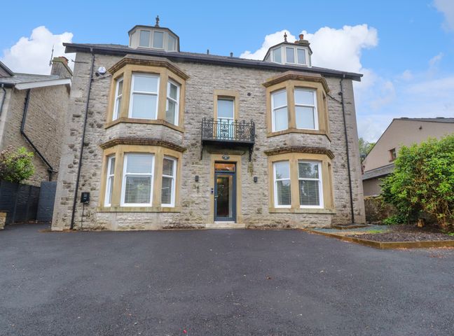 Stone house with bay windows and a driveway at The Oakroyd in Ingleton