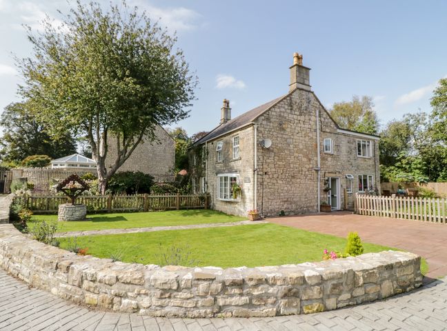 A stone house with garden and paved driveway surrounded by low stone wall at Crooked Well in Timsbury Nr Bath