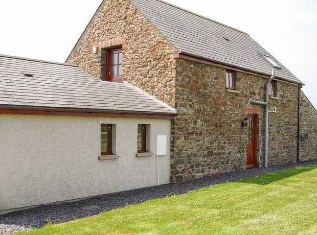 A stone and plaster house with a door and windows on a lawn at The Hagguard in Jeffreyston near Kilgetty