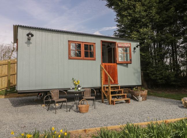 A small cabin with wooden steps and outdoor seating on gravel at Ewes Welcome in Cottingham