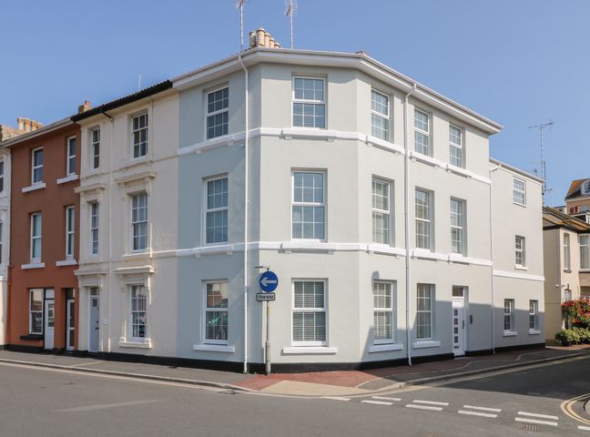 A three-story corner building with multiple windows and a one way street sign at Beach Rose in Teignmouth