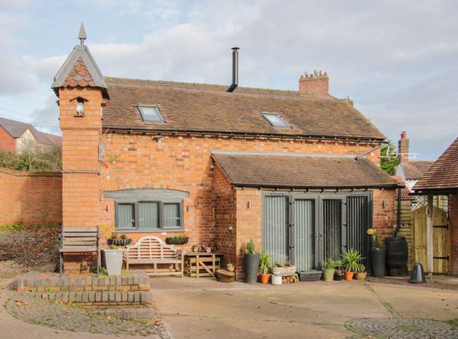 A brick house with skylights and several potted plants near the door at Bank House Barn in Hanwood