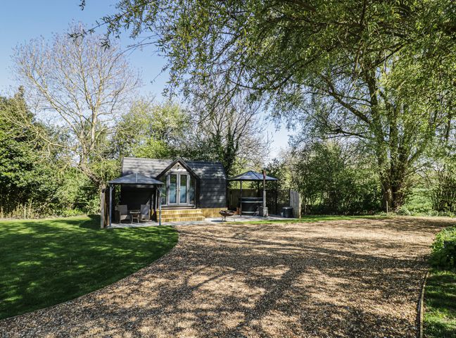 A cabin with a deck and seating area at Willow Lodge At Bridge Lake Farm & Fishery Chacombe