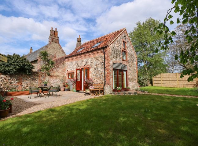 A stone and brick cottage with a tiled roof and a garden with outdoor furniture at The Little Hay Barn in Bacton