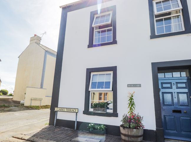 The exterior of a white house with black trim and blue door at 3 Clarks Terrace in Allonby