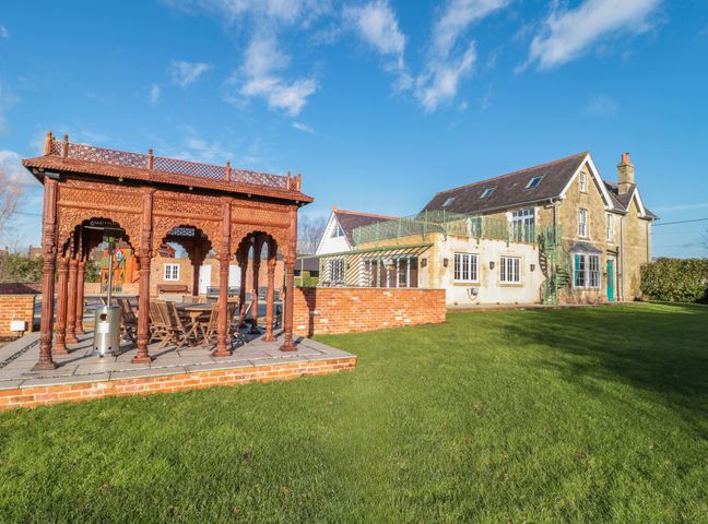 A house with a patio area and a wooden gazebo on a lawn at Royal Oak House in Motcombe