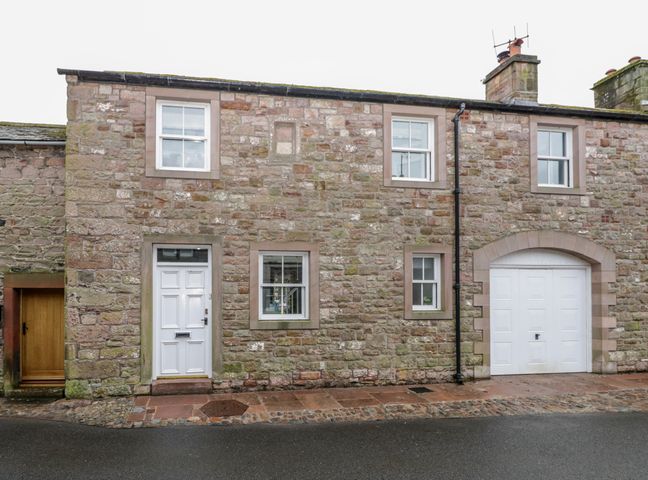 Stone house exterior with white doors and windows and a garage door at The Crook in Greystoke