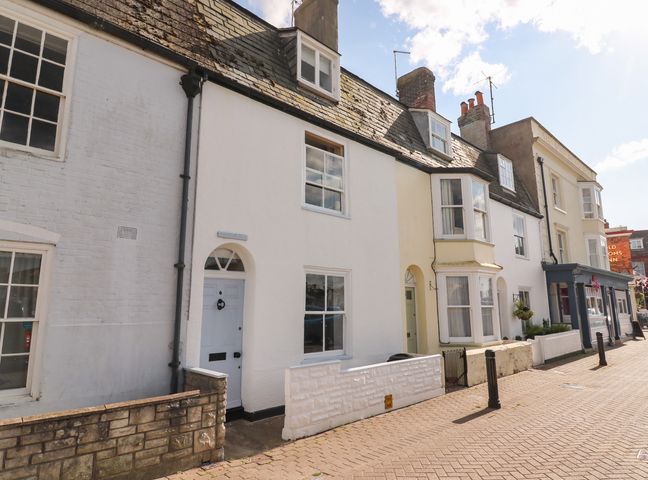 A row of terraced houses with white and yellow facades and a sidewalk at Brewers Quay Harbour